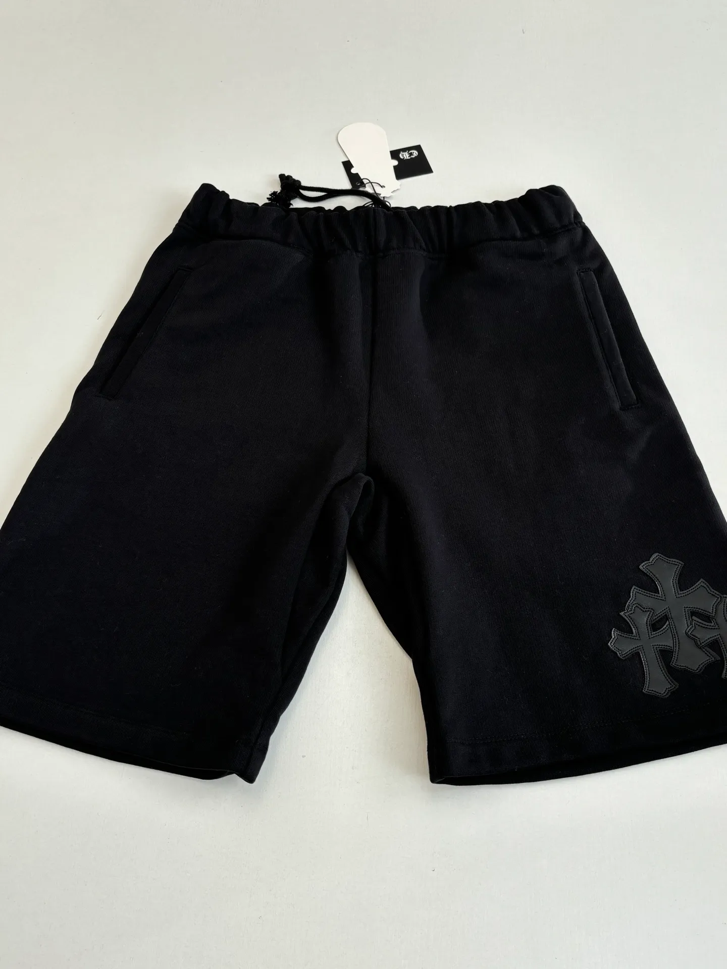 P346 Chrome Hearts*/Chrome Hearts 26SS early spring new patch embroidered shorts The fabric is made of a blended ratio of 80% cotton and 20% polyester. It is woven with a siro spinning process of 32-count base yarn and 10-count veil to form a high-weight terry cloth base of 380g/㎡. The cotton-polyester blended material combines the skin-friendly breathability of cotton and the anti-wrinkle shape retention of polyester. The high-weight fabric gives the trousers excellent stiffness and drape. The core technology is patch embroidery, which is completed with the help of TAJIMA computer embroidery machine. The black special-shaped patch is precisely sewn to the trouser fabric through lock stitches. The embroidery stitch density is even and the edges are neatly hemmed, forming a three-dimensional relief-like visual effect. Size: S/M/L/XL